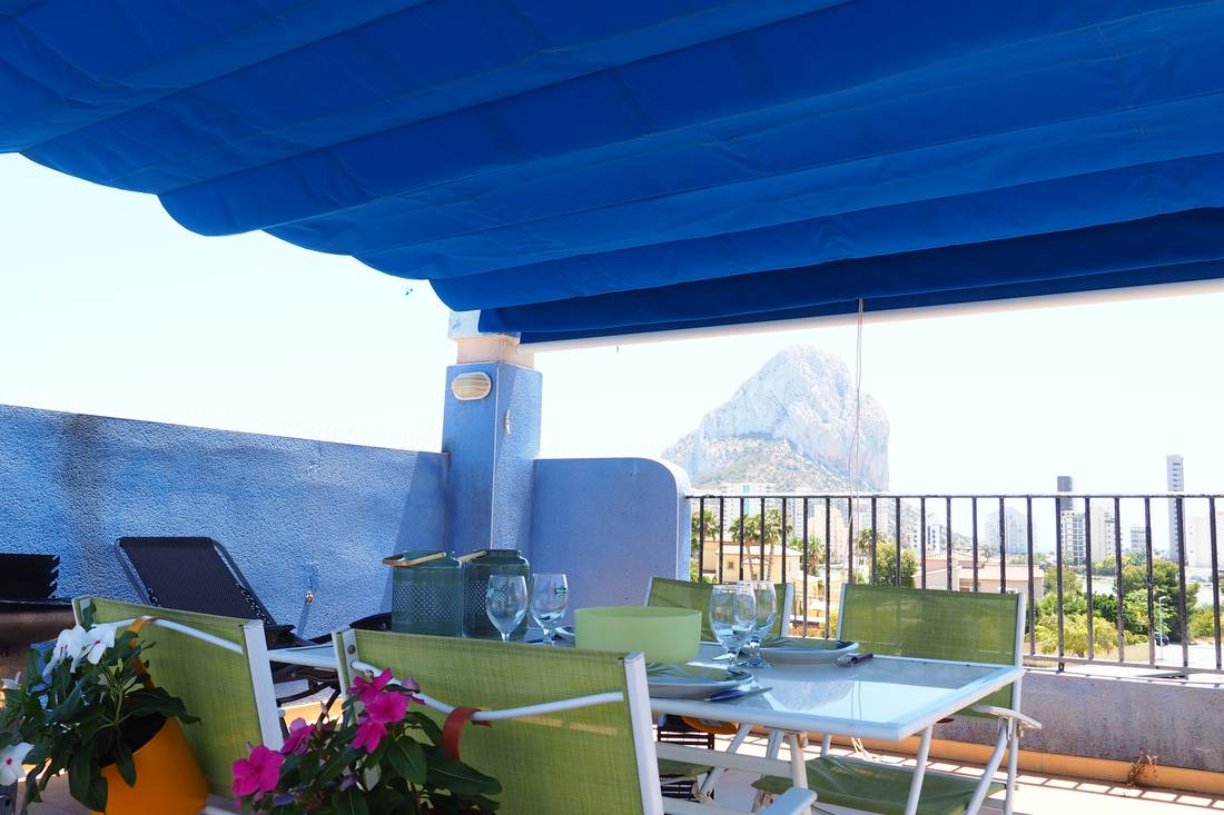 The terrace's blue awning against the sea and the Peñón