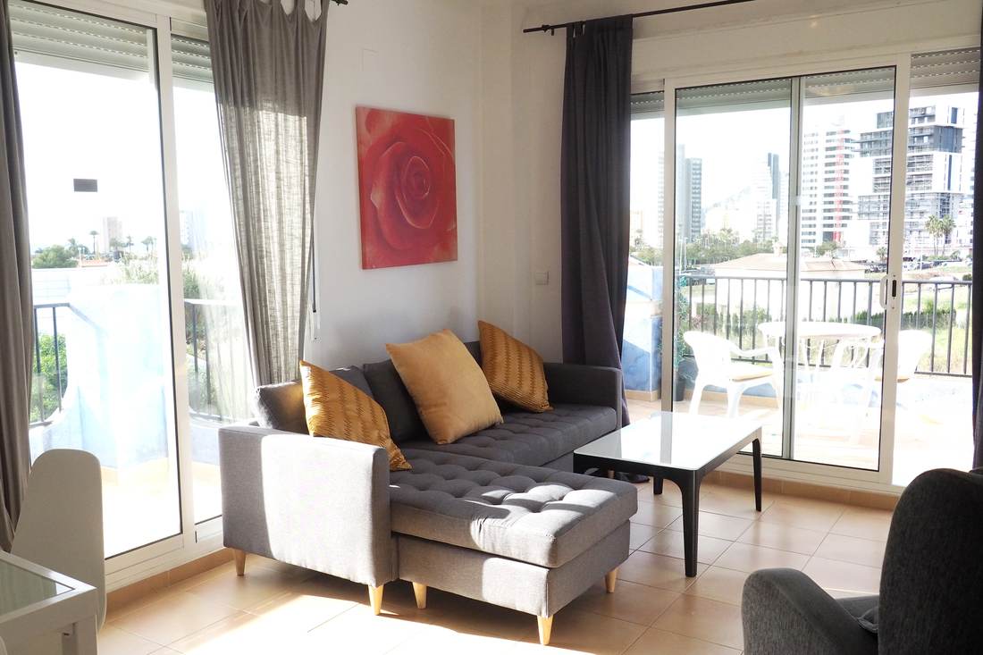 Living room with the grey sofa, the armchair and the sliding door to the terrace
