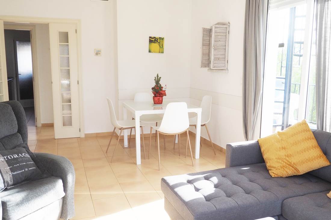 White dining area with the table, the chairs and the light coming in