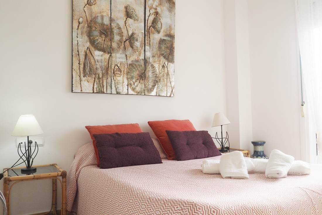 Double bedroom with red cushions and bedside tables on either side