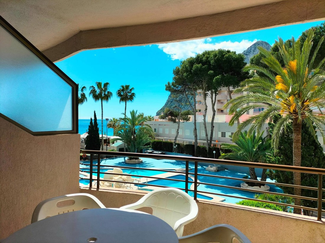The apartment's terrace with a table and chairs, looking over the pool