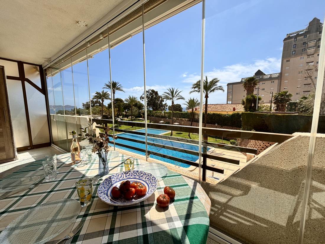 Terraza acristalada con la mesa puesta y la piscina al fondo