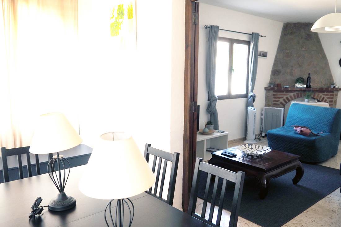 El salón con la chimenea de obra y la butaca azul