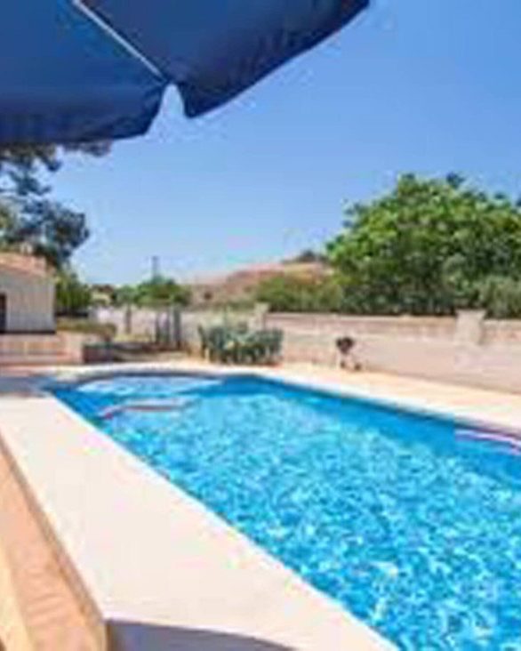The pool at Casa Clara with the blue parasol and the pines around it