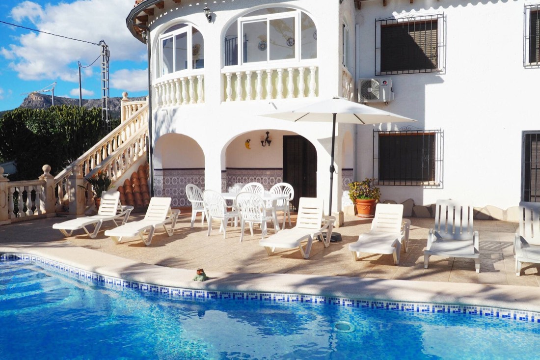 The white front of Casa Margarita with the pool and the sun loungers in the foreground