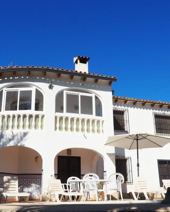 The front of Casa Margarita with the glazed gallery, the parasol and the terrace chairs