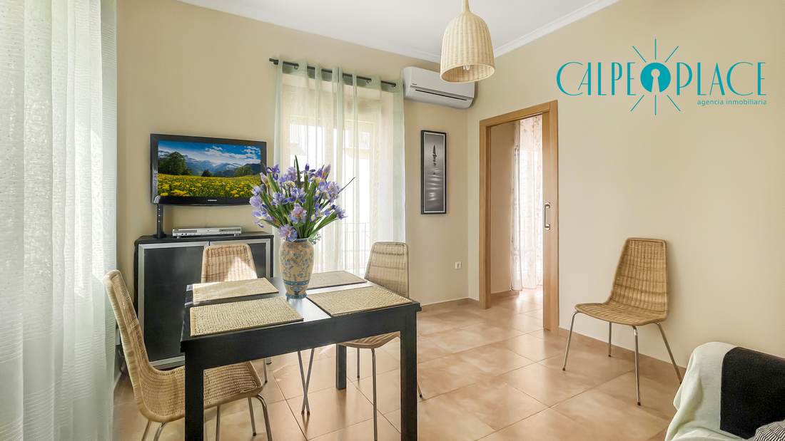 Salón comedor con el televisor y la cocina al fondo