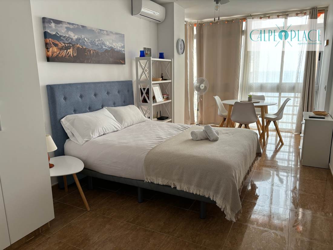 The bed with the small round table beside it and the terrace door open