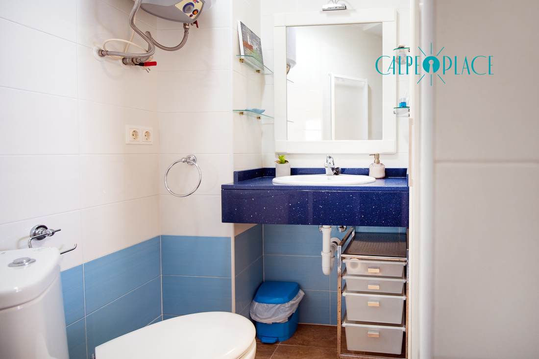 Full bathroom tiled in blue, with basin, toilet and bidet