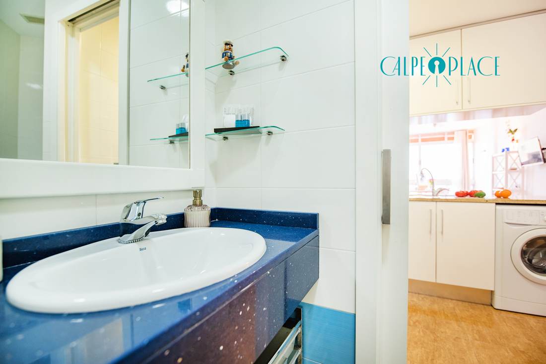 The bathroom basin with a mirror and the way through to the kitchen behind