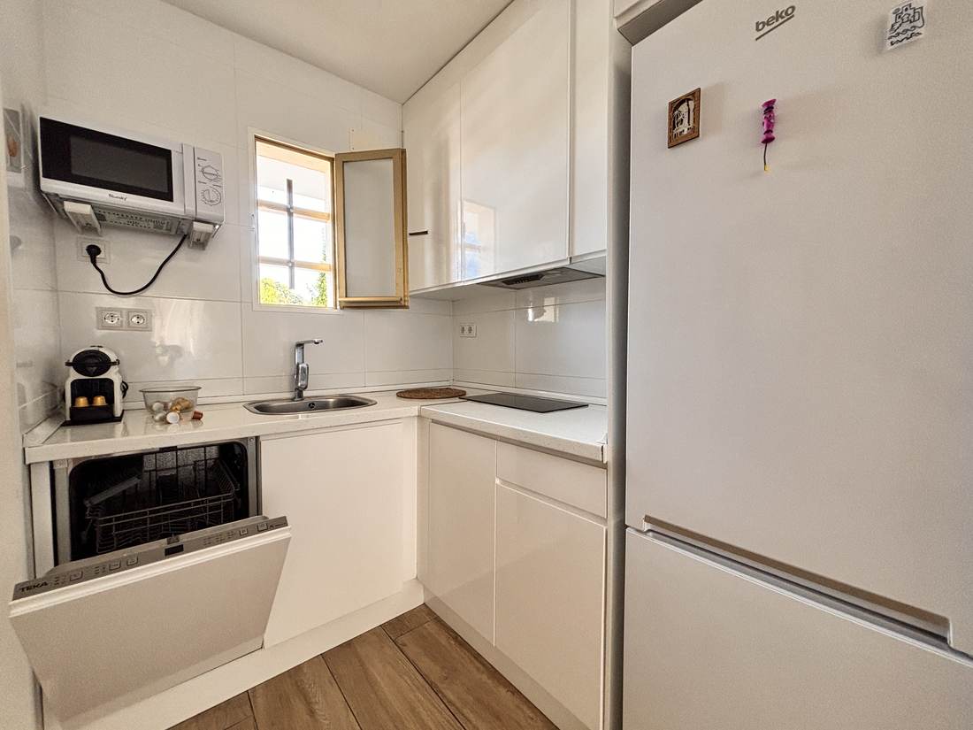 Cocina blanca con microondas, vitrocerámica y nevera