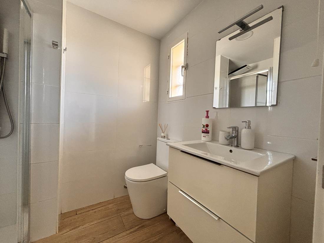 Baño con mueble de lavabo blanco y espejo