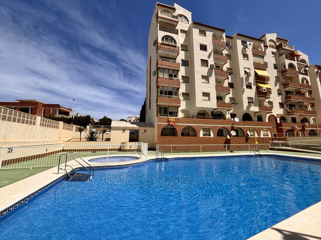 La piscina con el edificio de ladrillo al fondo