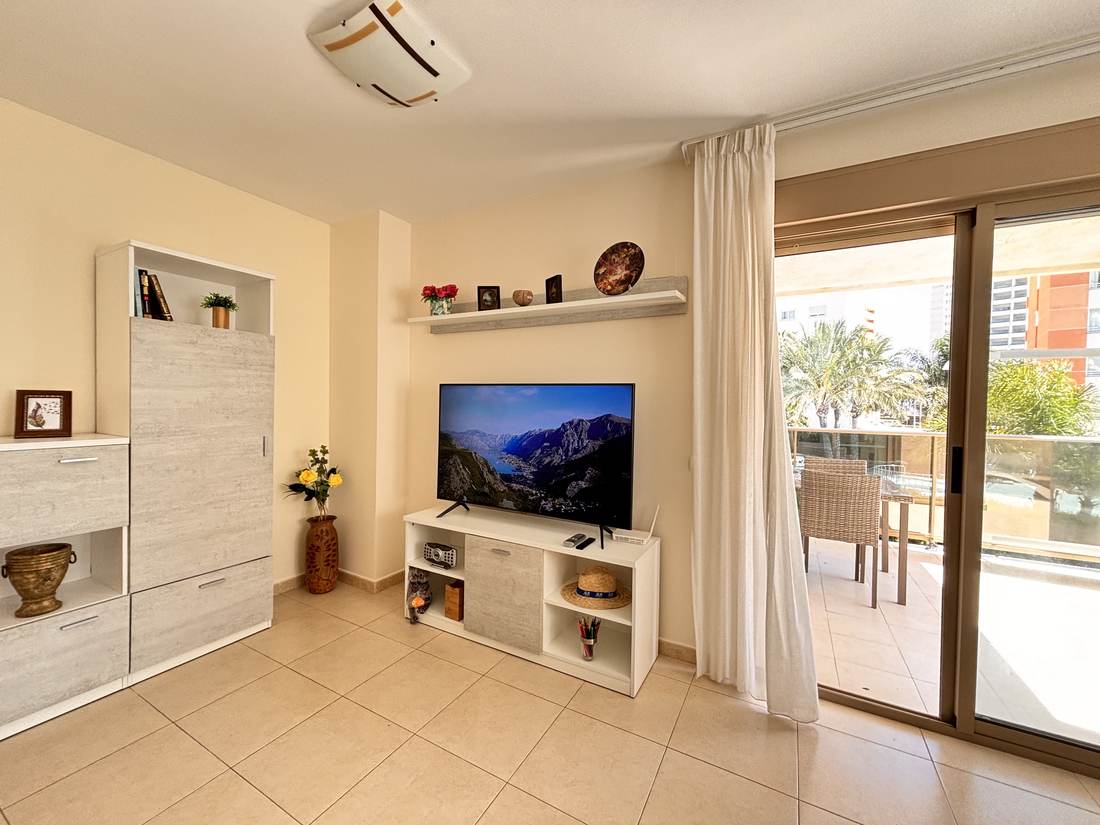 Living room with sofa, TV and the way out to the terrace