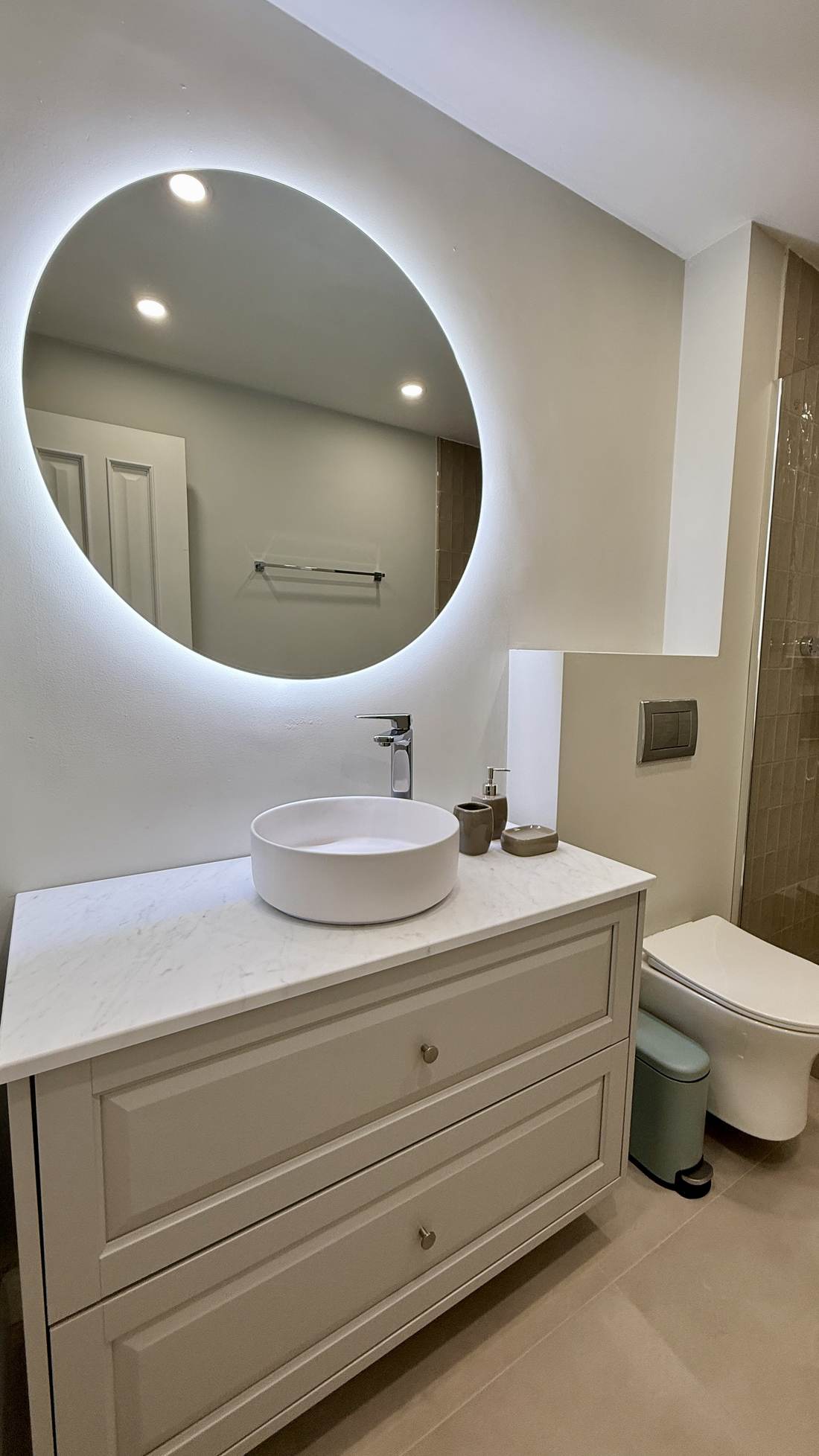 Bathroom with a round backlit mirror and vanity unit