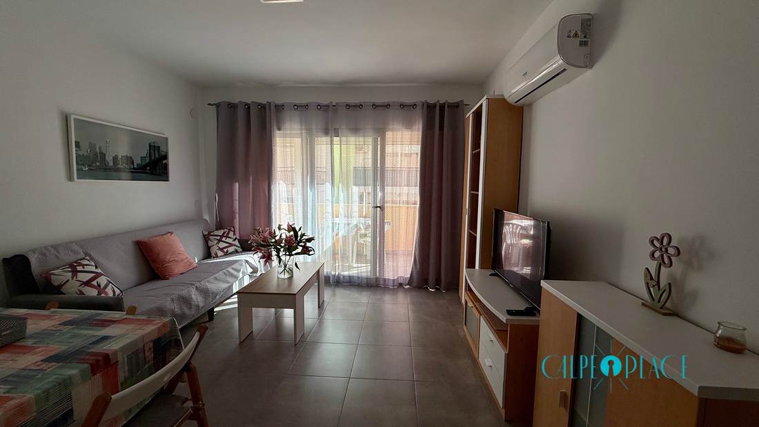 Living room with a grey sofa and the sliding door to the terrace