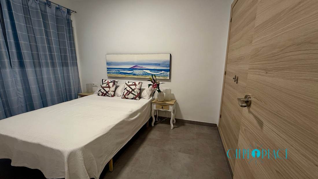 Bedroom detail, with the bed made and the picture of the sea