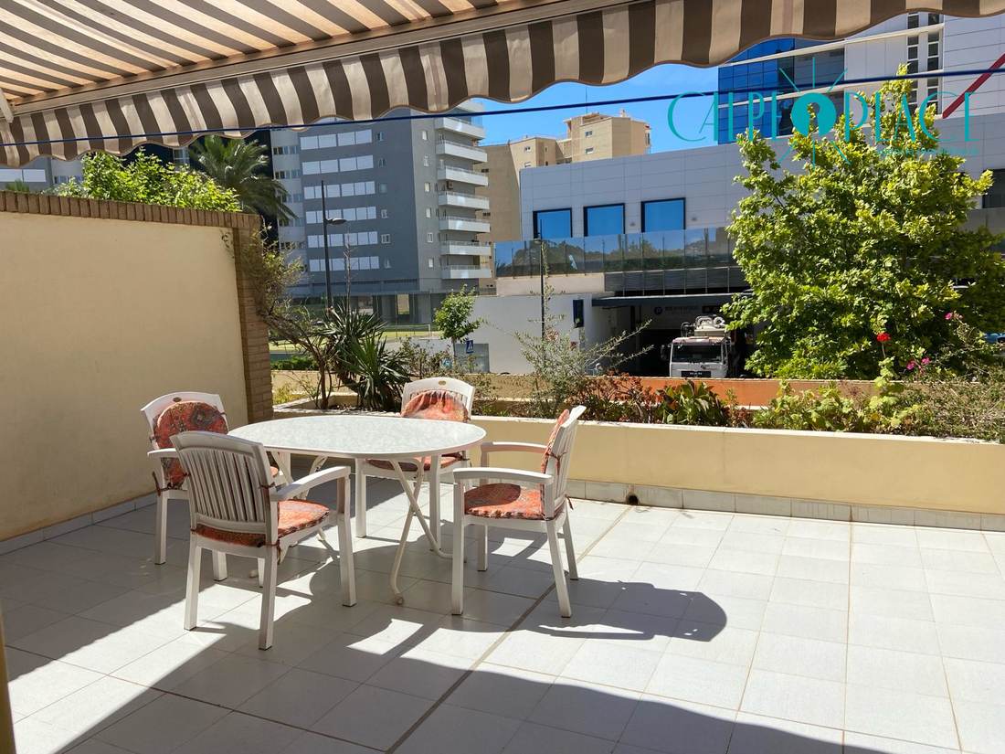 Terraza con mesa y sillas, sobre los jardines de la urbanización