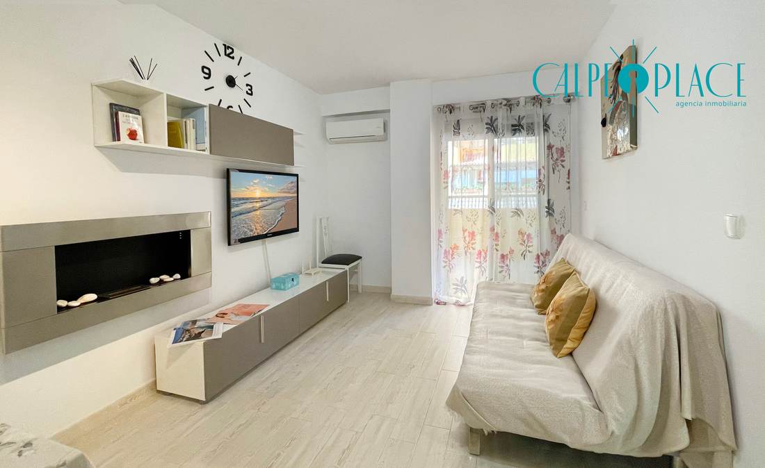 Salón de Jardín con el sofá blanco y el mueble bajo de televisión