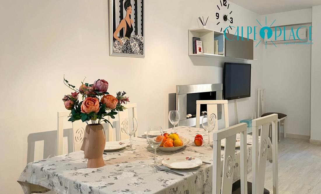 Comedor con la mesa puesta y la televisión al fondo