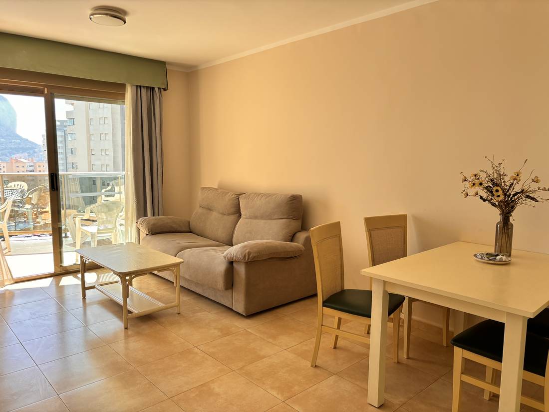 Salón con sofá y mesa de comedor junto al ventanal de la terraza