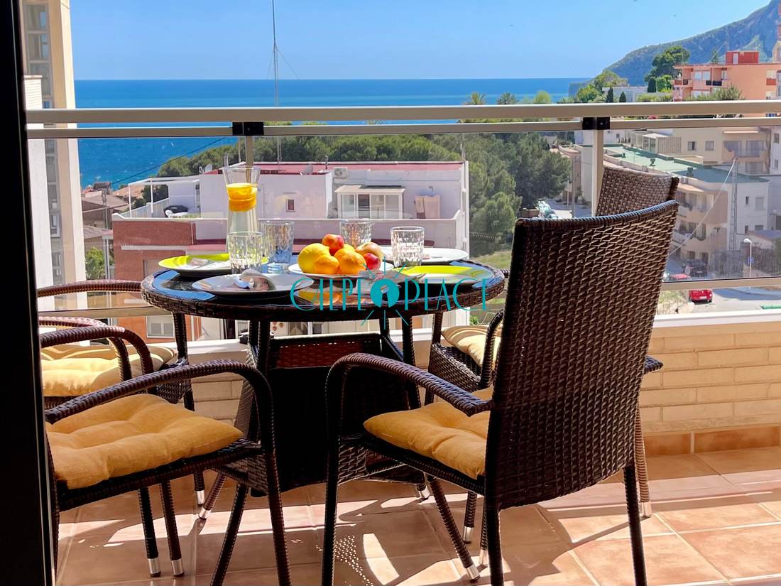 Terraza con la mesa y las sillas de mimbre y el mar al fondo