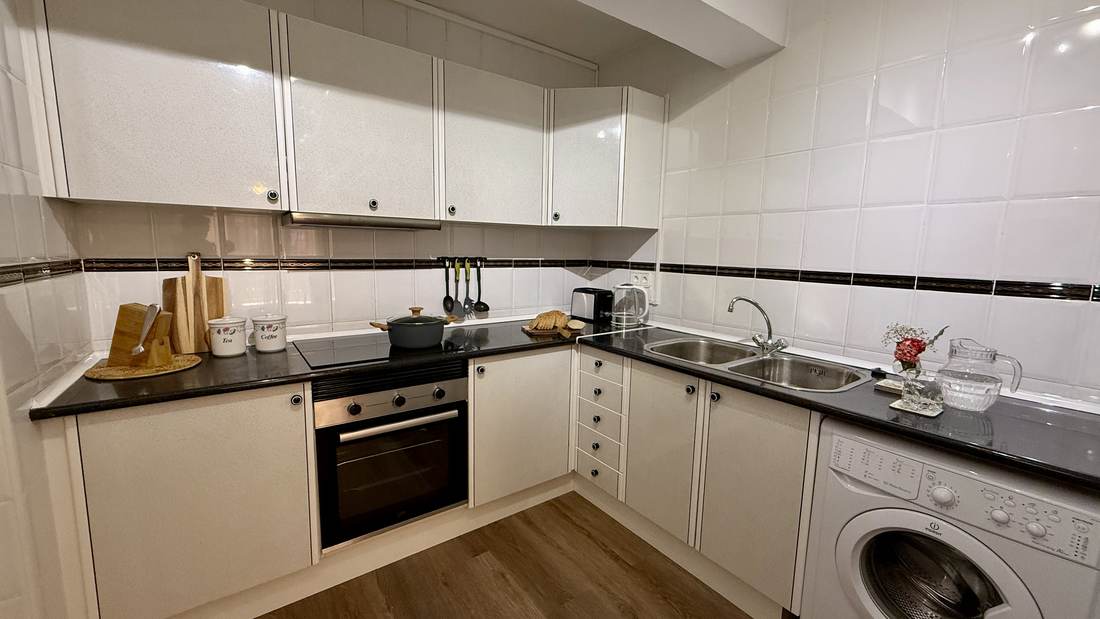 Cocina reformada en blanco, con encimera negra y horno