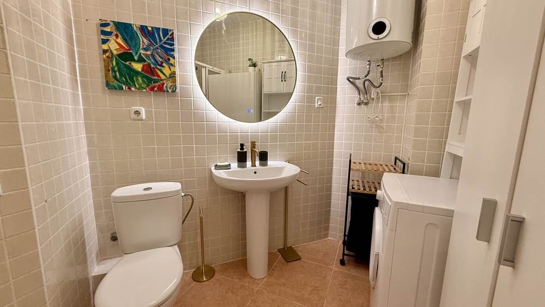 Baño reformado con espejo redondo retroiluminado