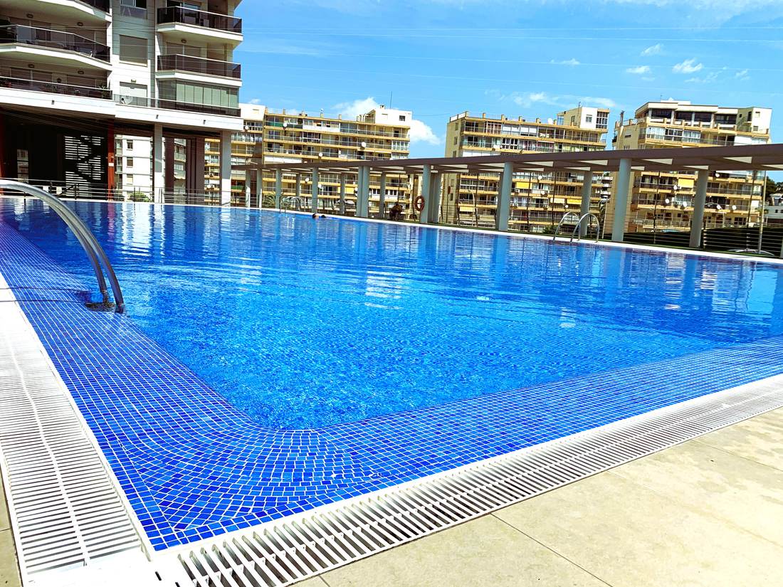 Piscina comunitaria del edificio Entremares, con el césped y las tumbonas