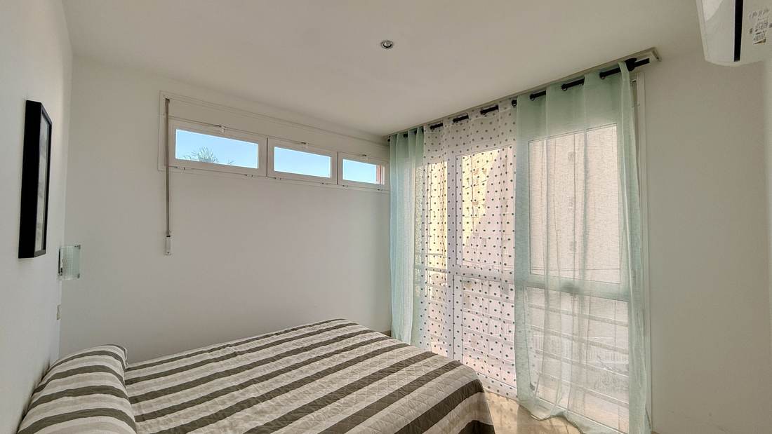 Bedroom with a striped bedspread and air conditioning