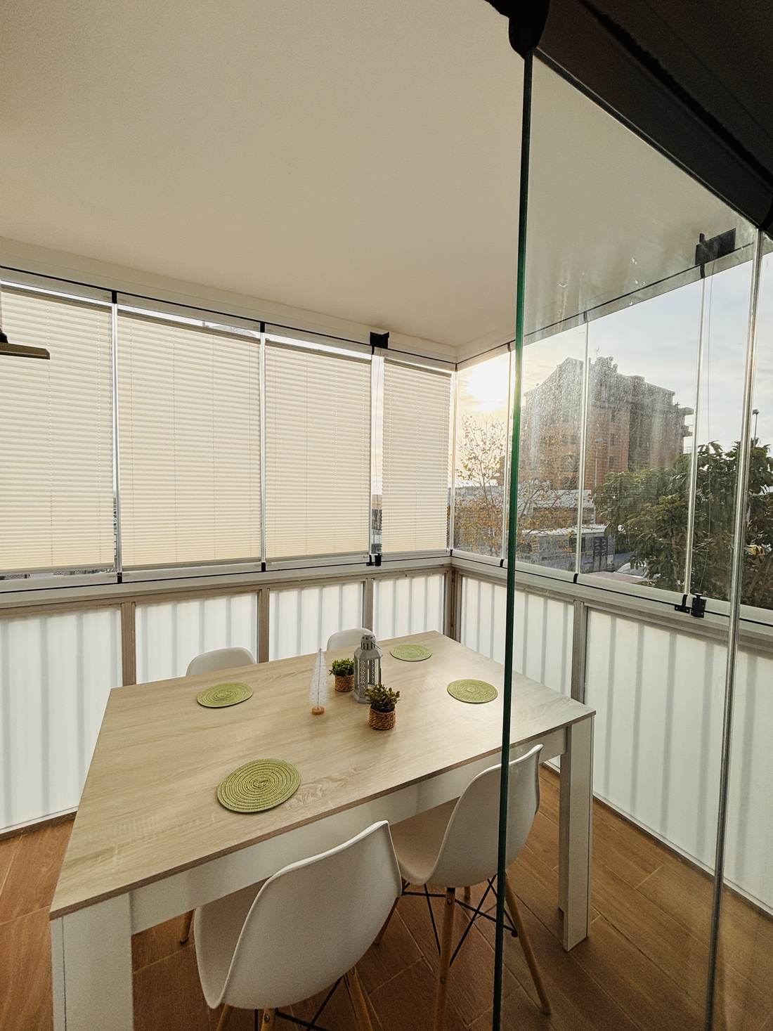Galería acristalada usada como comedor, con mesa blanca y sillas