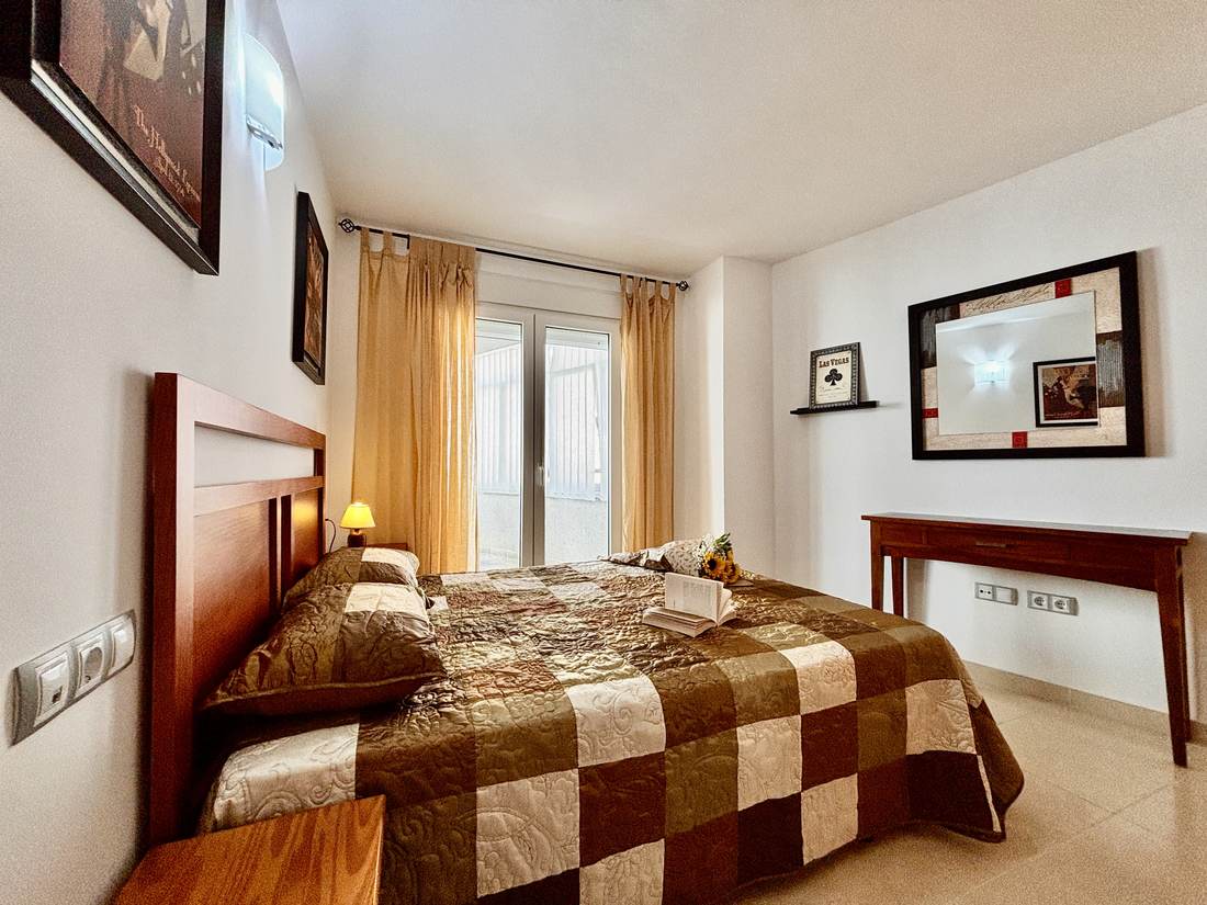 Dormitorio con cama de matrimonio y colcha de cuadros