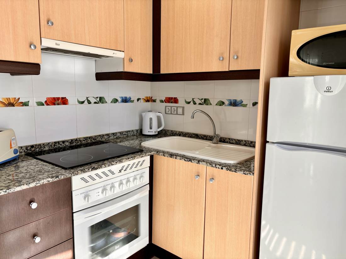 Cocina con vitrocerámica, horno y nevera