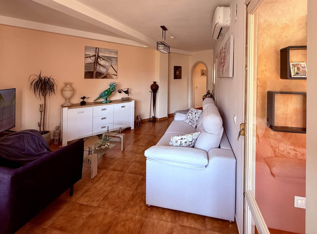 Salón con sofá blanco, suelo de barro y las vistas por el ventanal