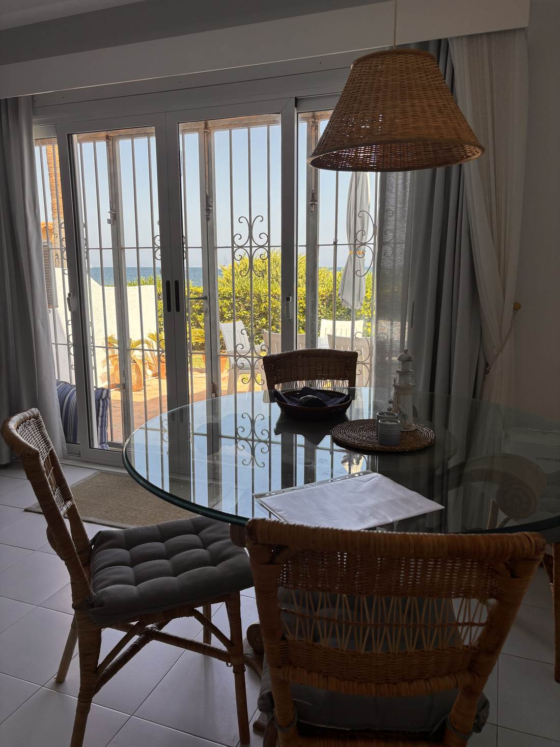 Terraza con mesa y sillas de mimbre, con el mar al fondo