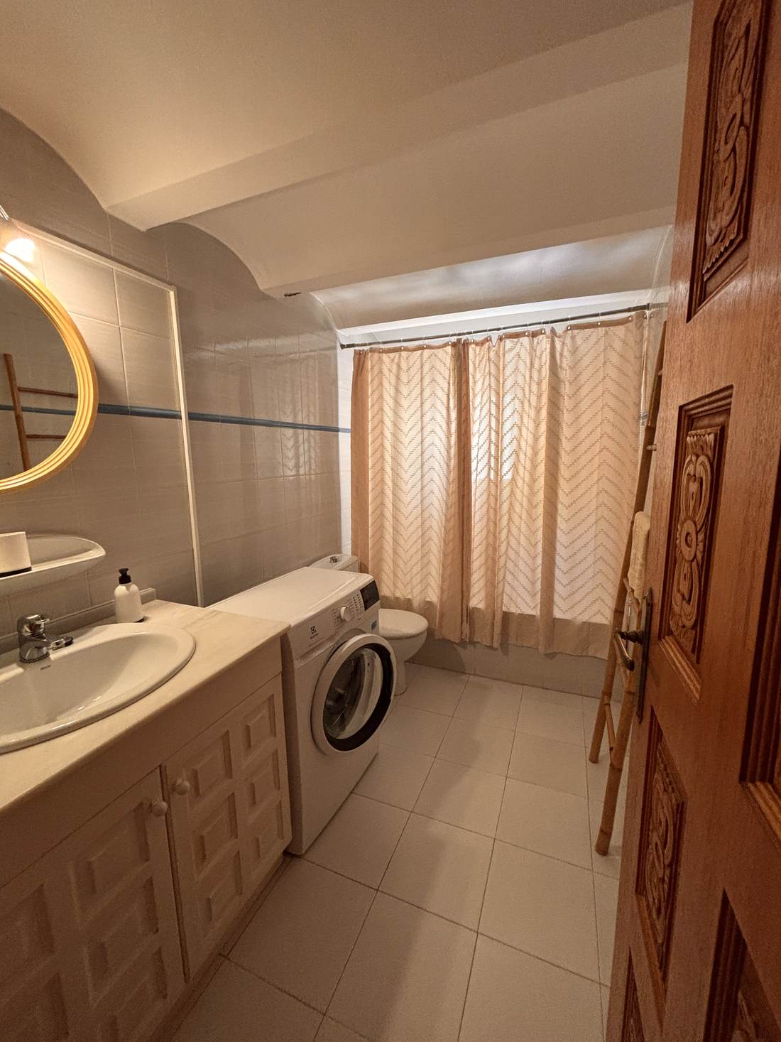 Baño con lavabo, espejo redondo y ducha