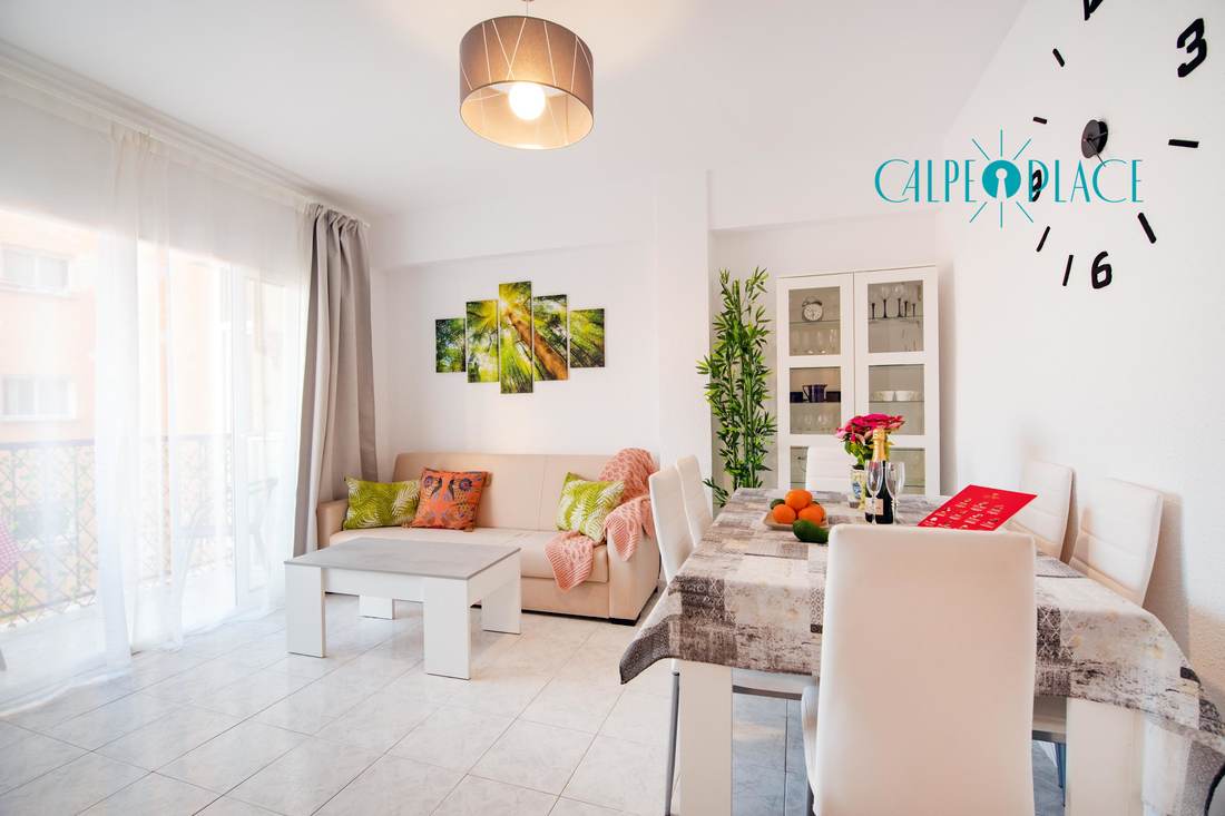 The living room seen from the dining area, with the coffee table and the plants