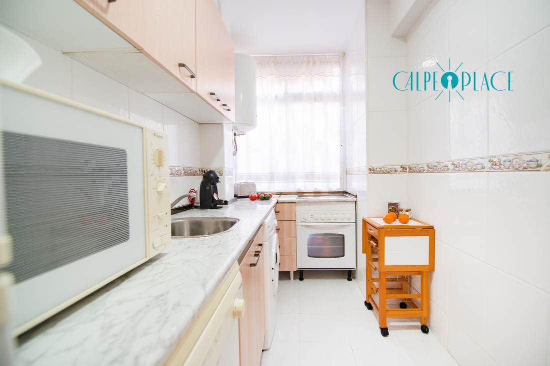 The long galley kitchen from end to end, with the worktop and white units