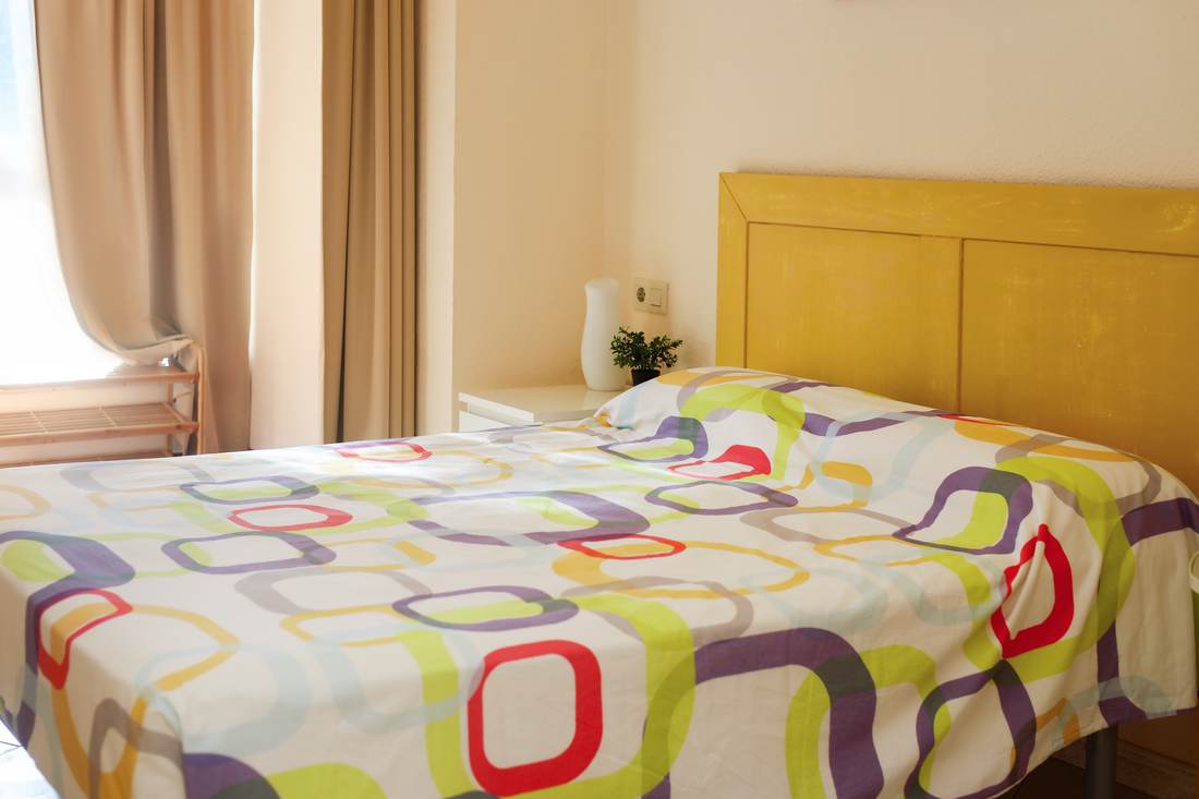 Bedroom with a colourful bedspread and a yellow headboard