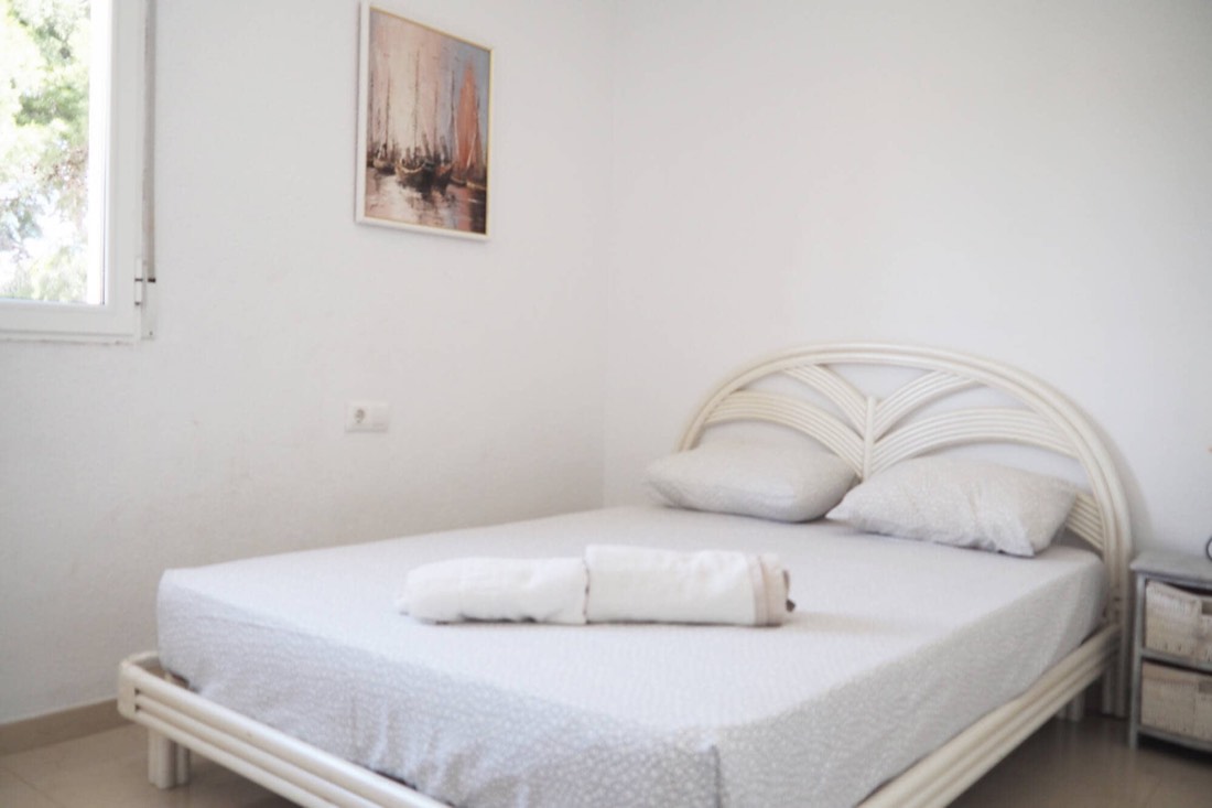 Dormitorio doble con cabecero blanco y las toallas preparadas