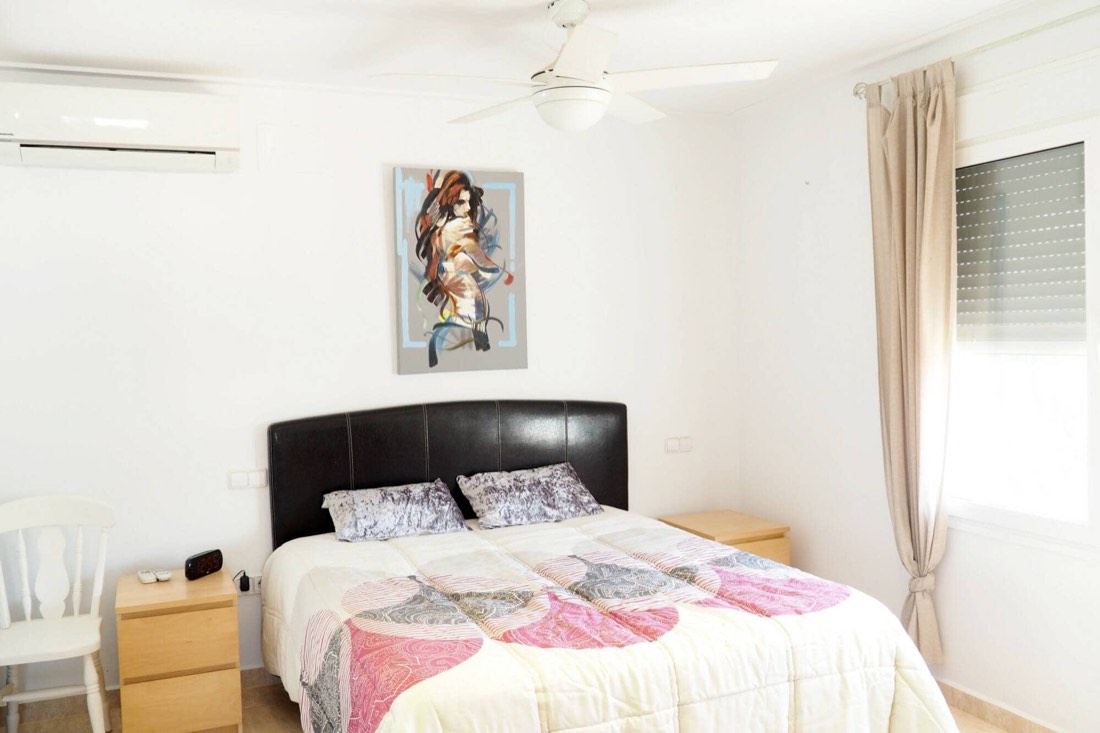 Dormitorio de matrimonio con cabecero oscuro y aire acondicionado