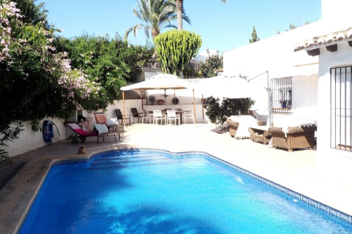 Piscina privada de Villa Ricarlos con las sombrillas, los sofás de exterior y el jardín