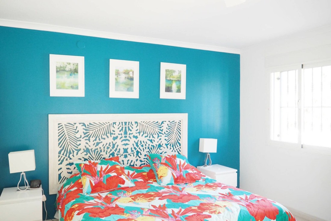 Dormitorio doble con la pared turquesa y colcha de flores