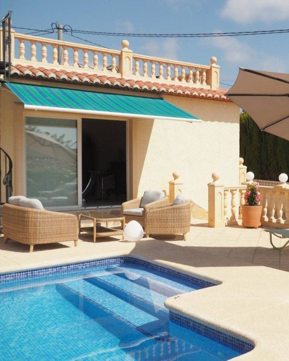 The terrace at Villa Yasmin with wicker armchairs under the awning and the pool in front