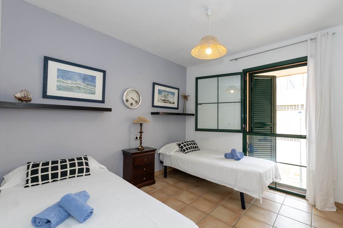 Dormitorio con dos camas individuales y toallas dobladas