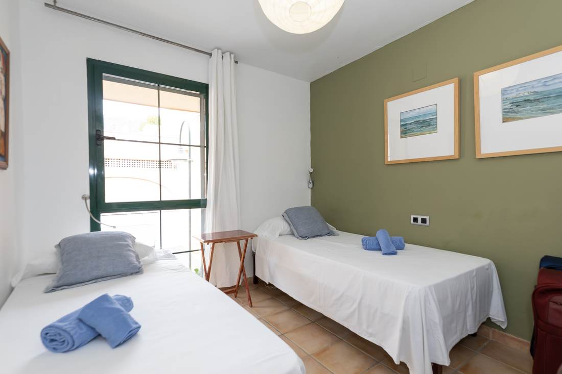 Tercer dormitorio, con dos camas individuales y la pared verde