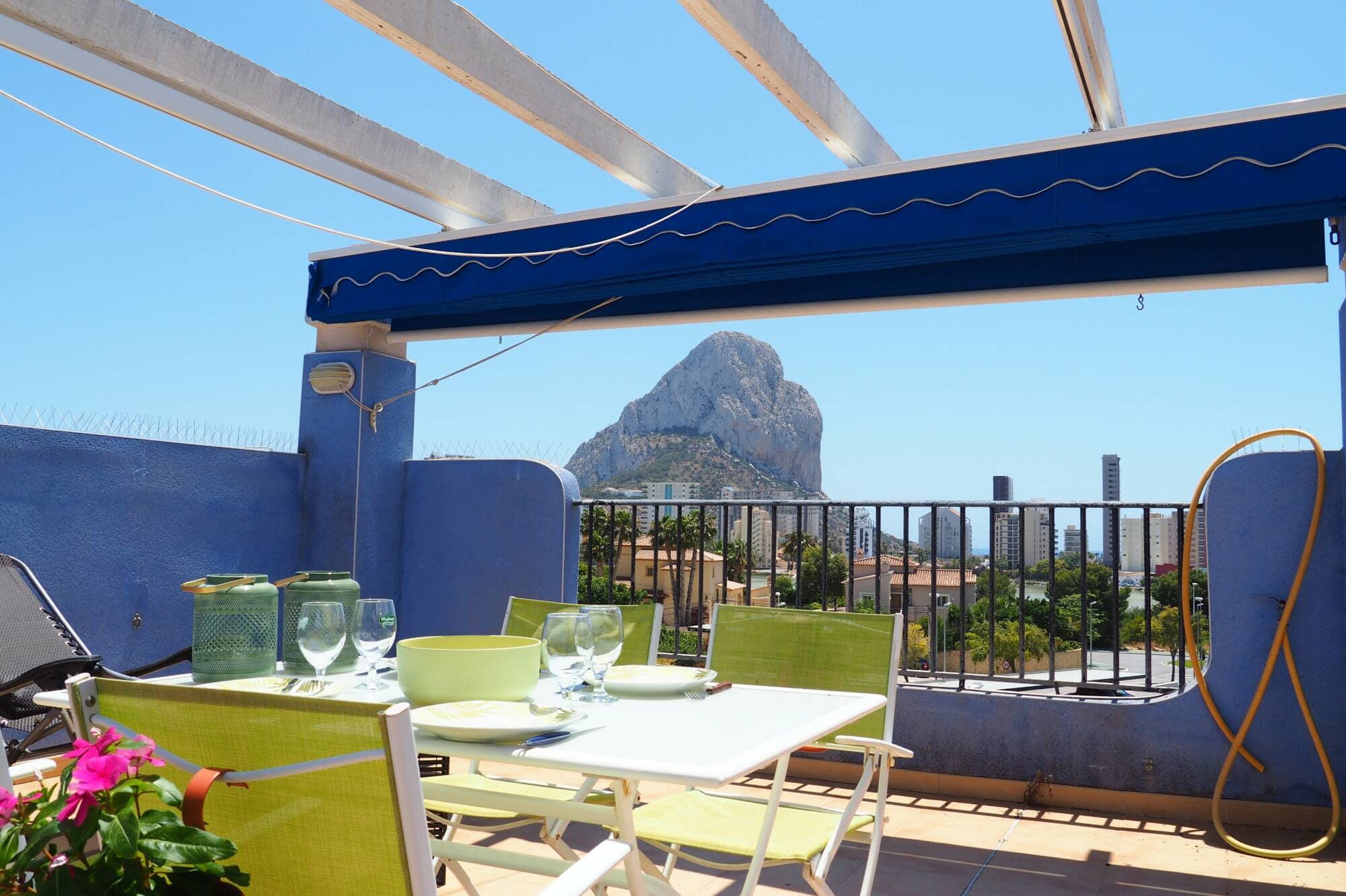 An apartment terrace in Calpe with the table laid under the awning and the Peñón de Ifach behind