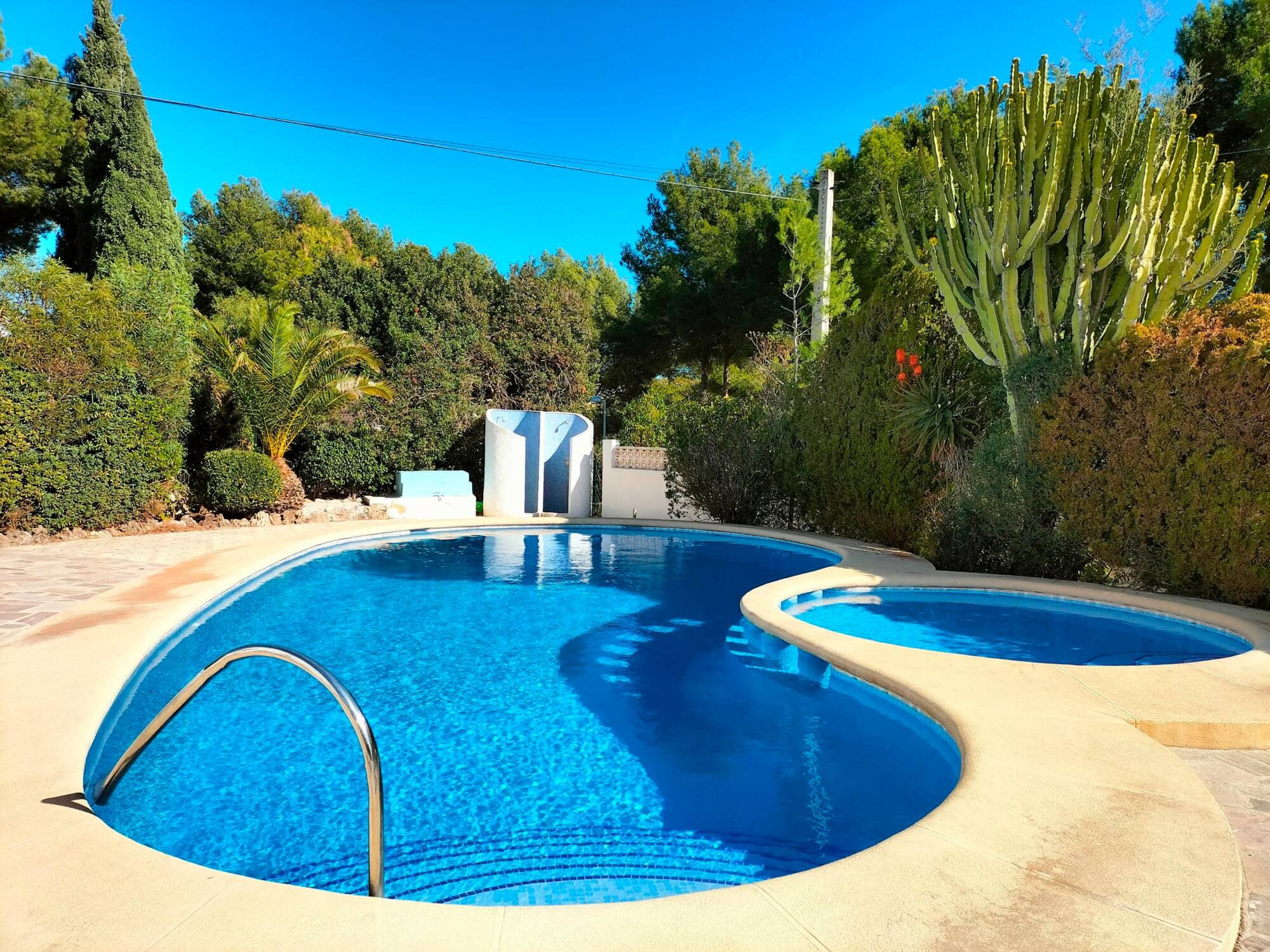 A curved communal pool surrounded by Mediterranean planting in Calpe